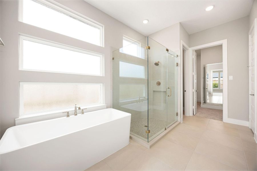 A freestanding soaking tub and glass-enclosed walk-in shower create a spa-like feel in the primary bath, framed by tall windows for natural light. A freestanding soaking tub and glass-enclosed walk-in shower create a spa-like feel in the primary bath, framed by tall windows for natural light.