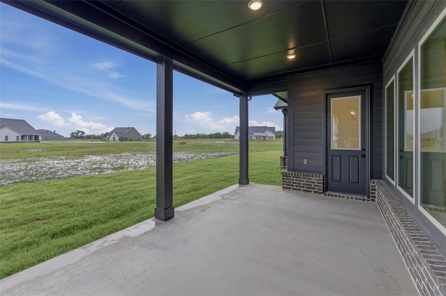Concrete covered patio with recessed lighting, dark siding, and a glass-paneled exterior door Concrete covered patio with recessed lighting, dark siding, and a glass-paneled exterior door