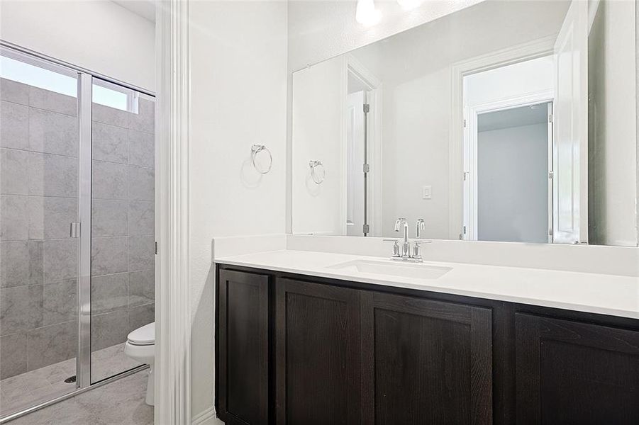 Bathroom featuring walk in shower, vanity, and toilet