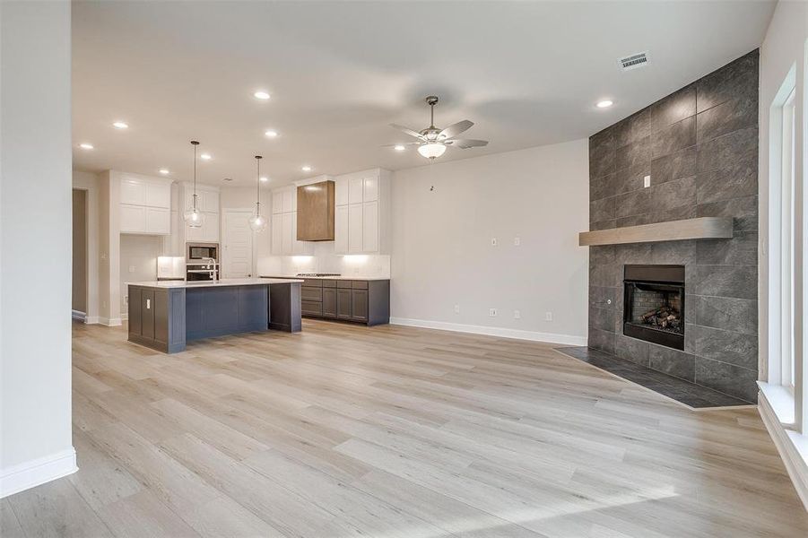 Kitchen with ceiling fan, light hardwood / wood-style floors, decorative light fixtures, a center island with sink, and white cabinets