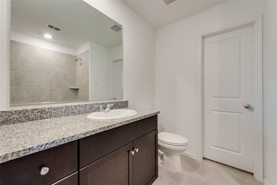 Full bathroom featuring vanity, light tile patterned floors, and a tile shower Full bathroom featuring vanity, light tile patterned floors, and a tile shower