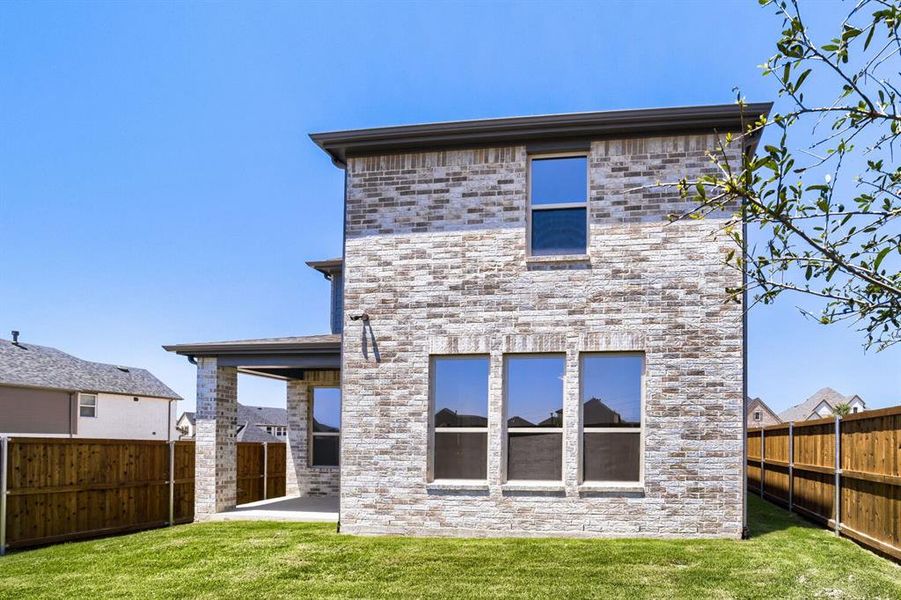 Brick veneer exterior with a covered patio, three ground-floor windows, an upper-level window, and a wood privacy fence