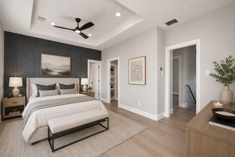 Spacious primary suite featuring a tray ceiling, designer accent wall, & warm contemporary finishes for a relaxing retreat.