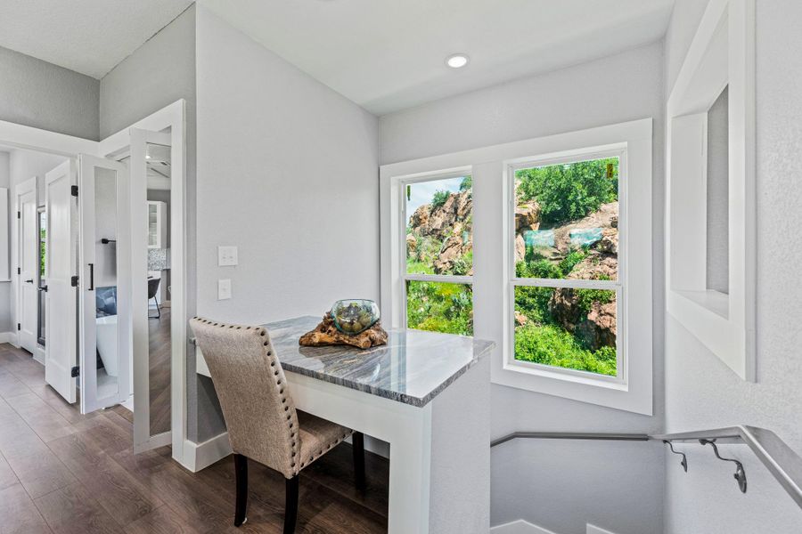 Built-in desk featuring a stone countertop, double windows, and wood-finish flooring