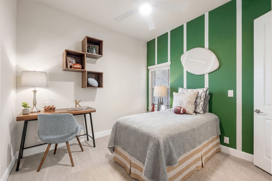 Kids' bedroom with football-themed green accent wall, twin bed, and small wooden desk with wall shelves