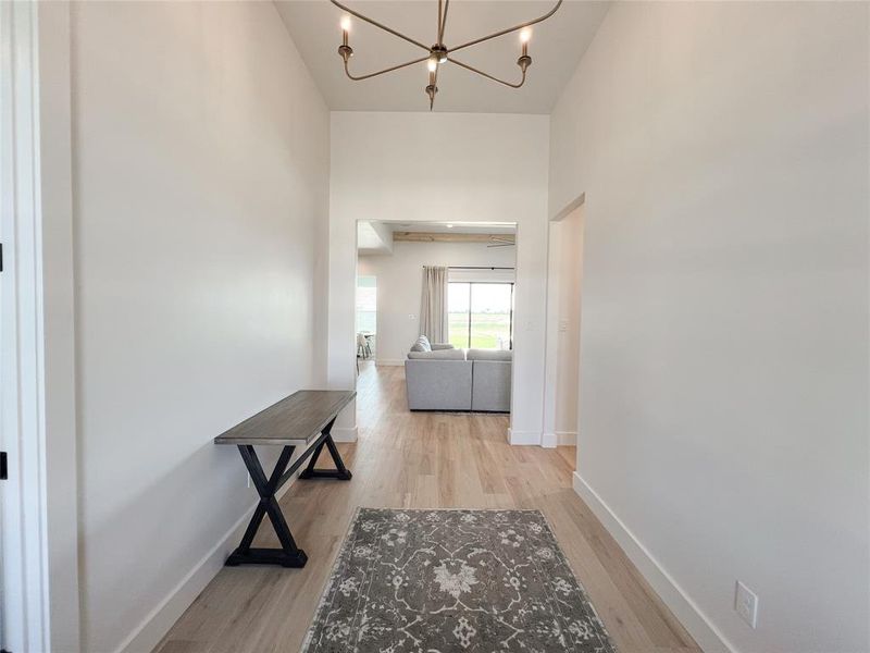 Hallway with light wood-style flooring and a chandelier