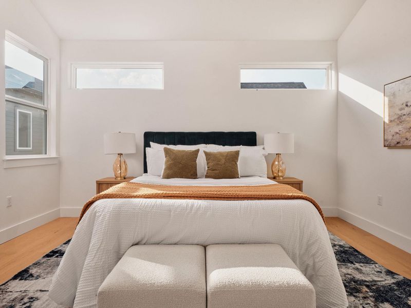 Bright bedroom featuring light wood-finish flooring and white walls