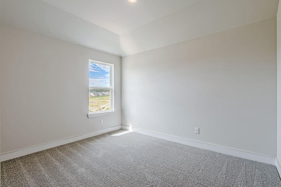 Bright and airy secondary bedroom with soft neutral tones, plush carpet, and large windows offering peaceful neighborhood views and abundant natural light.