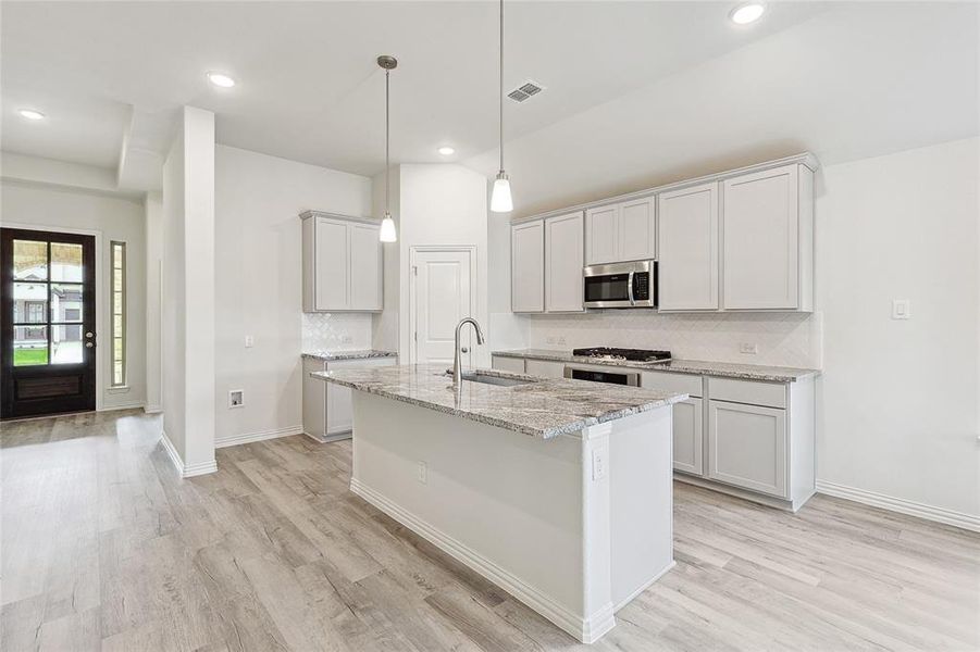 Kitchen featuring light hardwood / wood-style floors, sink, decorative backsplash, and stainless steel appliances