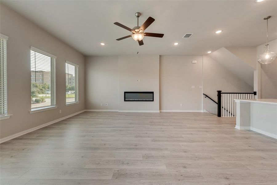 Unfurnished living room featuring ceiling fan and light wood-type flooring