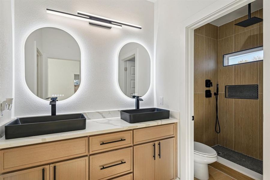 Full bath with double vanity, walk in shower, and a textured wall