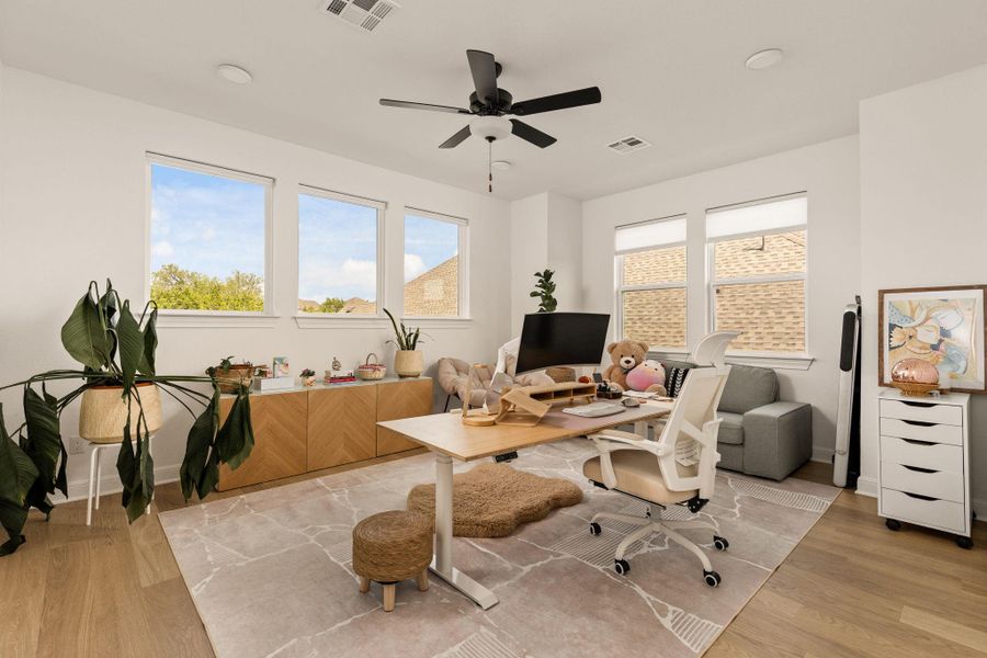 Spacious room featuring multiple windows, recessed lighting, a ceiling fan, light wood-finish flooring, and a built-in cabinetry unit with a chevron pattern