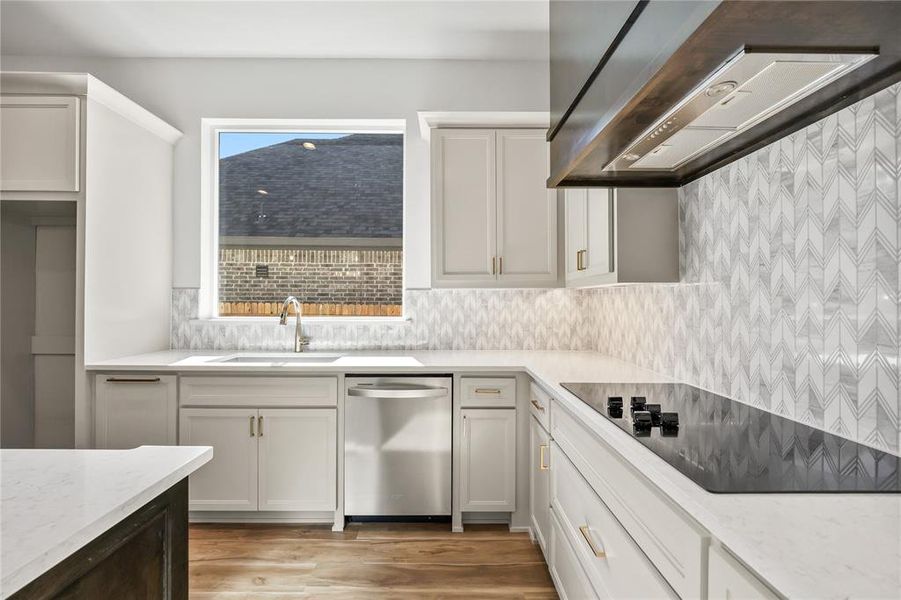 Kitchen featuring custom exhaust hood, white cabinetry, stainless steel dishwasher, light stone counters, and black electric stovetop