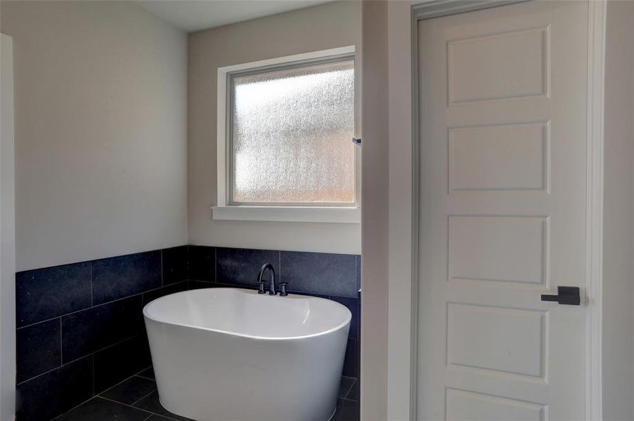 Bathroom featuring tile walls, tile patterned flooring, and a tub