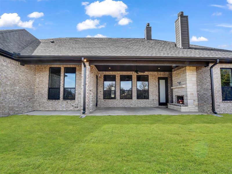 Back of house with a yard, a patio, and exterior fireplace