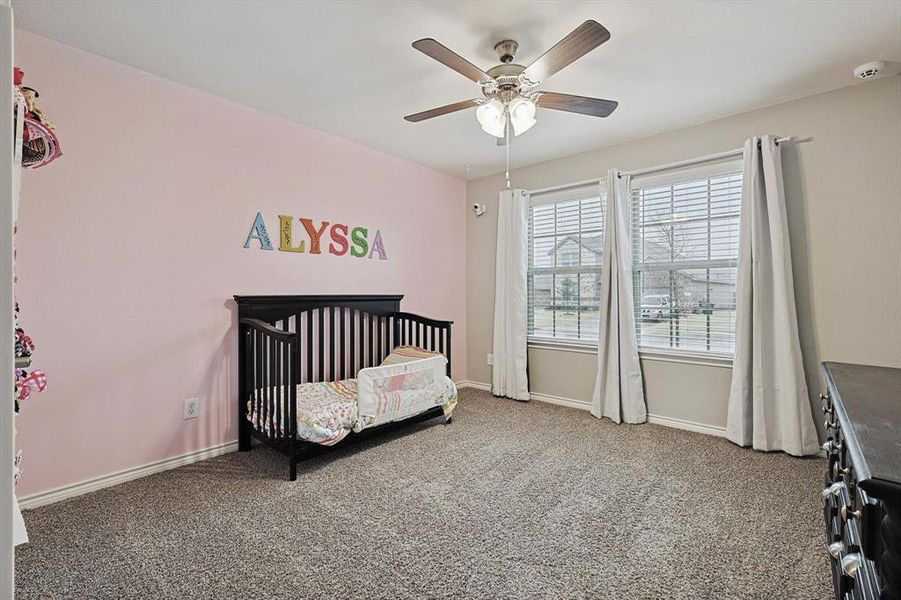 Bedroom featuring a crib, carpet flooring, and ceiling fan