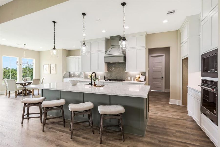 Open-concept kitchen featuring a large marble island with seating, sleek cabinetry, and stainless steel appliances. Open-concept kitchen featuring a large marble island with seating, sleek cabinetry, and stainless steel appliances.