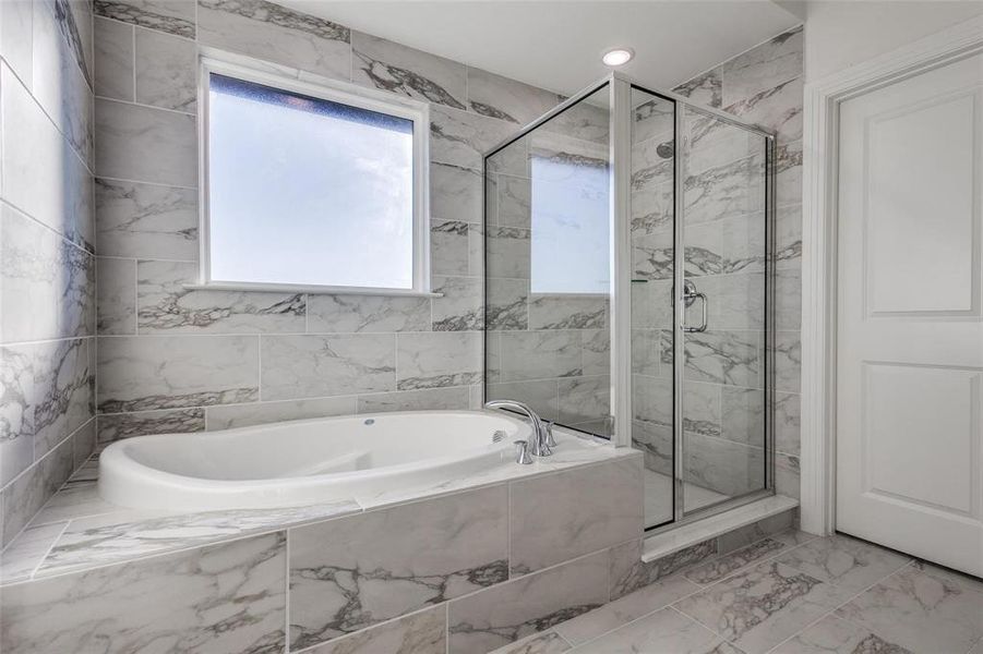 Full bath with a marble finish shower, light marble finish floors, and a garden tub Full bath with a marble finish shower, light marble finish floors, and a garden tub