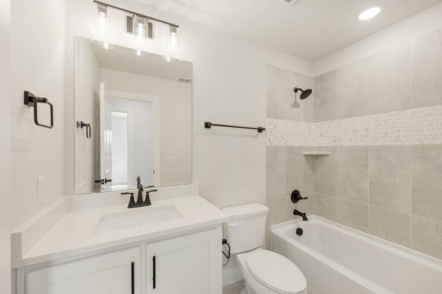 Bathroom with white vanity, tub-shower combo with gray tile surround, and matte black fixtures