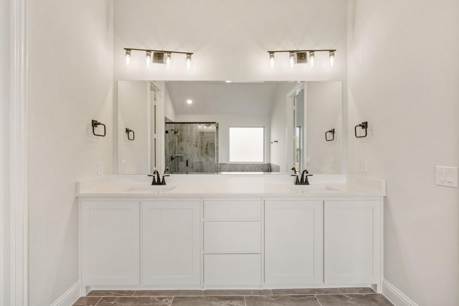 Bathroom double vanity with white cabinets, quartz countertop, large mirror, and dual vanity lights