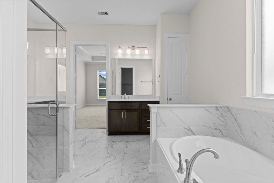 Another perspective of the primary bath showcasing the seamless flow between the shower, soaking tub, and vanity area.