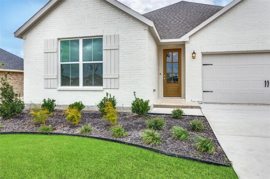 View of front facade featuring a garage and a front lawn