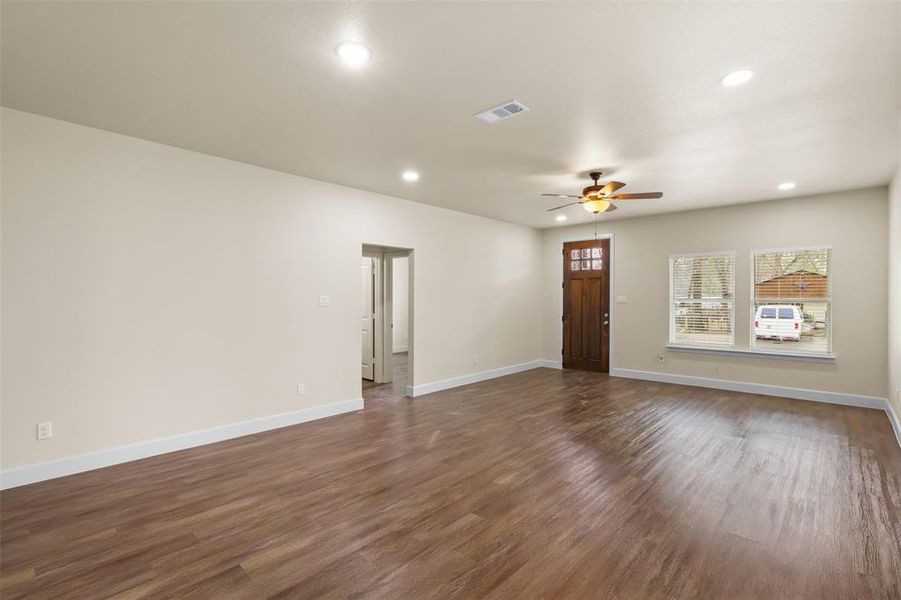 Unfurnished living room with plenty of natural light, dark hardwood / wood-style floors, and ceiling fan