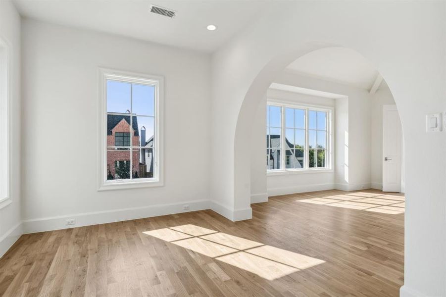 Primary bedroom featuring light hardwood floors and a wealth of natural light