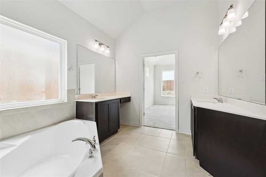 Bathroom featuring tile patterned flooring, a washtub, lofted ceiling, and a healthy amount of sunlight