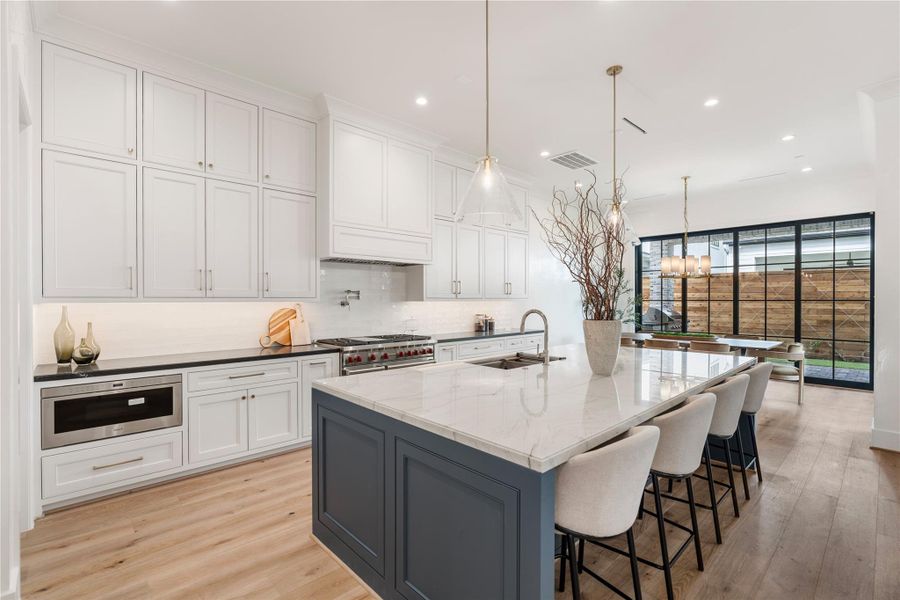The gold tones of the drawers pop on the white cabinetry, while they also contrast the darker island elegantly, exuding a modern yet traditional feel. All cabinetry is built on-site and includes soft-close mechanisms, inset doors, and undermount drawer hardware.