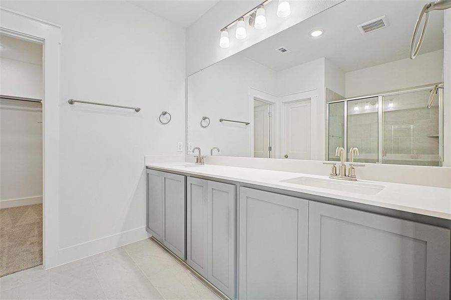 Full bathroom with double vanity, a stall shower, a walk in closet, tile patterned flooring, and recessed lighting