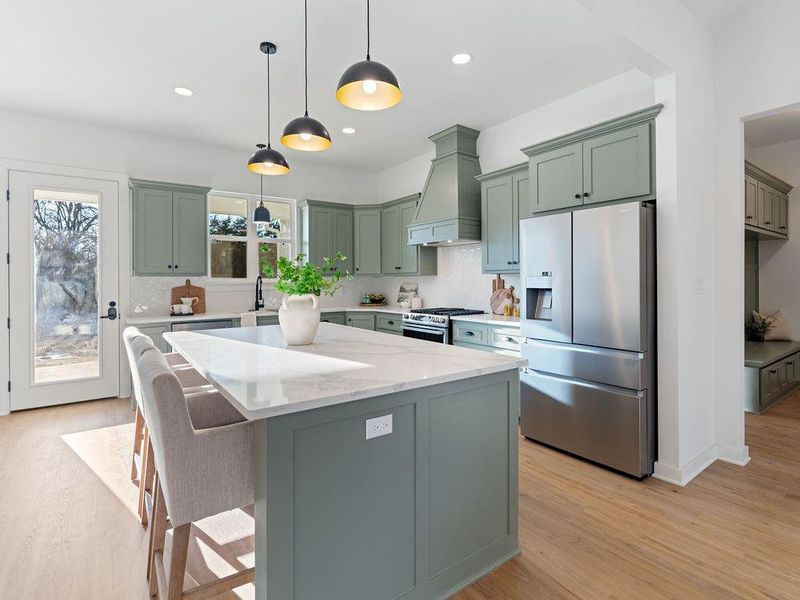 Kitchen with stainless steel appliances, a kitchen breakfast bar, a center island, light wood-style flooring, and light stone counters