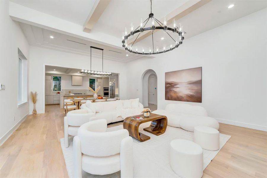 Living area with arched walkways, beamed ceiling, light wood-style floors, recessed lighting, and a chandelier Living area with arched walkways, beamed ceiling, light wood-style floors, recessed lighting, and a chandelier