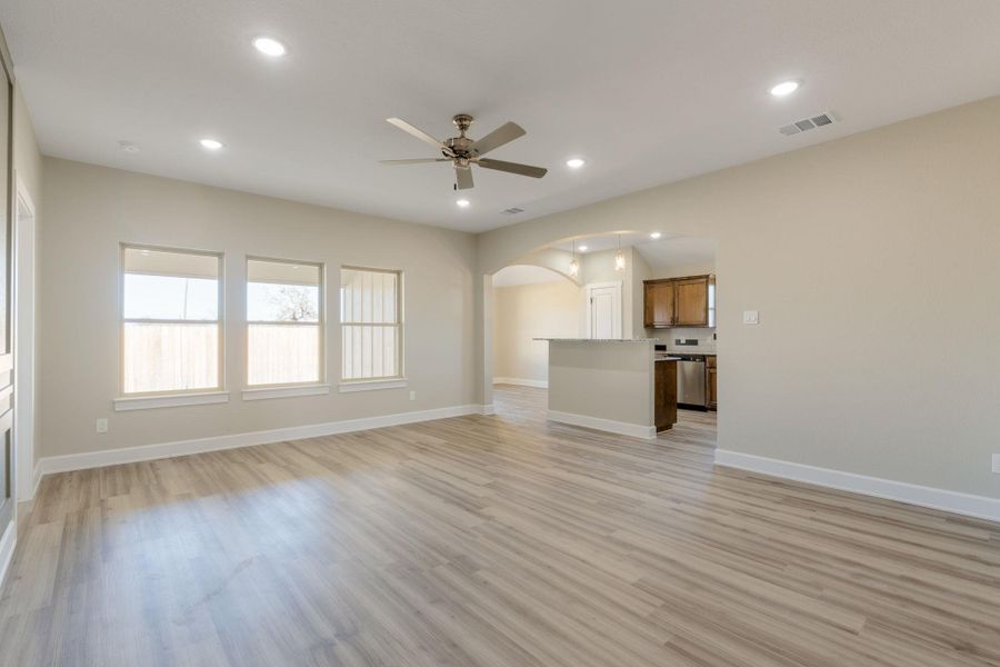 Unfurnished living room with ceiling fan, arched walkways, light wood-type flooring, and recessed lighting