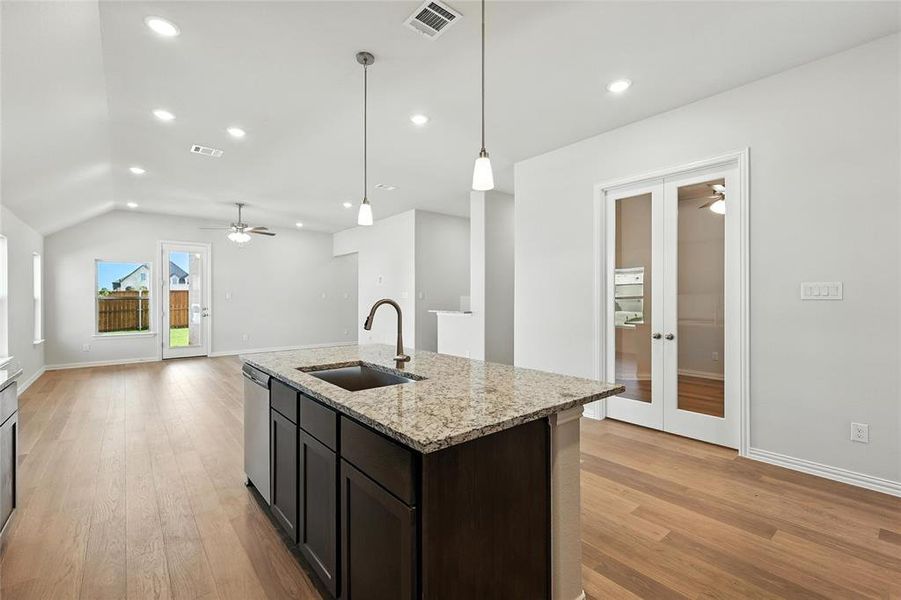 Kitchen featuring ceiling fan, light stone counters, light wood finished floors, french doors, and lofted ceiling