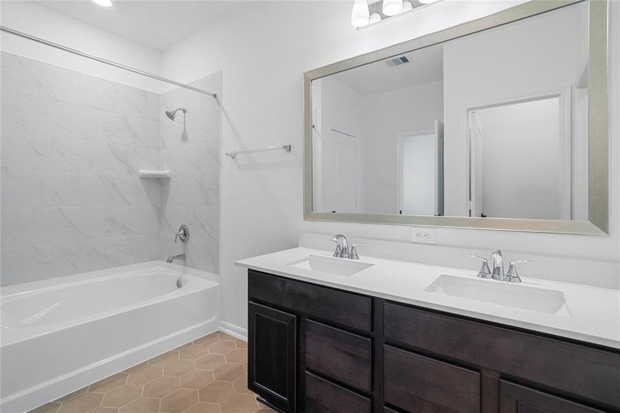 This primary bathroom is definitely move-in ready! Featuring an oversized tub and shower combination with tile surround, stained cabinets with light countertops and dual vanities, high ceilings, neutral paint, sleek and modern finishes.