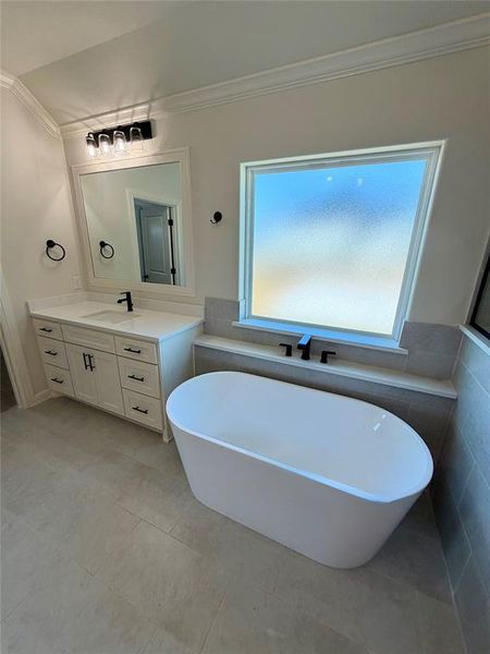 Bathroom with vanity, a freestanding tub, ornamental molding, and tile walls Bathroom with vanity, a freestanding tub, ornamental molding, and tile walls