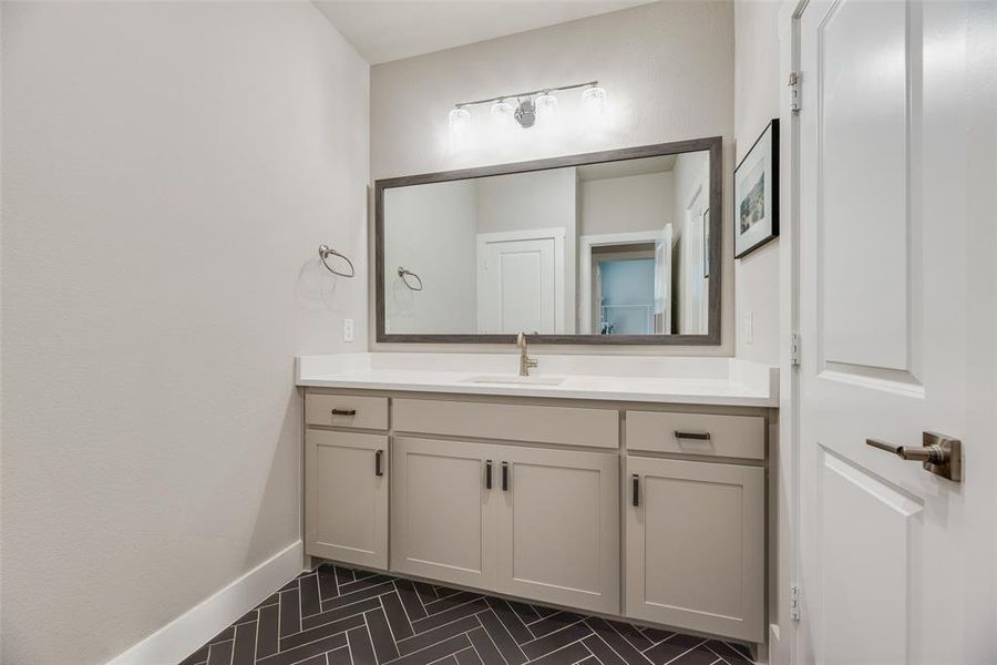 Modern vanity featuring a single basin, light-toned countertop, and ample storage cabinetry