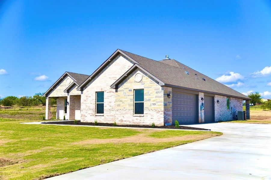 View of front of property featuring brick siding, concrete driveway, a front yard, and a 3 car garage