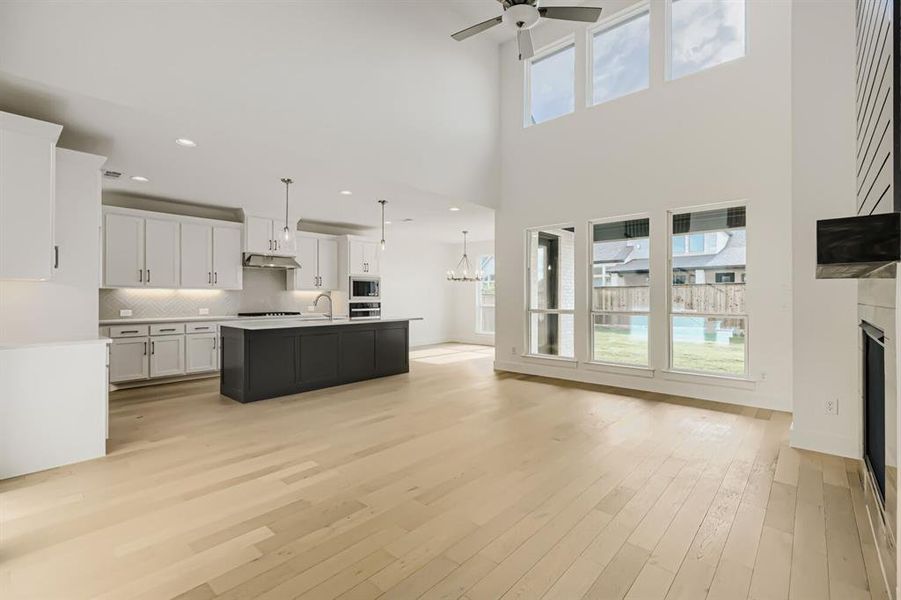 Kitchen featuring open floor plan, an island with sink, light countertops, a fireplace, and a ceiling fan