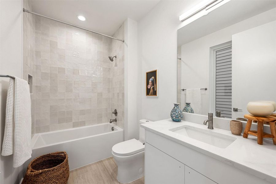 Modern bathroom featuring elegant tiled walls, a pristine bathtub, and a chic vanity with ample counter space. Modern bathroom featuring elegant tiled walls, a pristine bathtub, and a chic vanity with ample counter space.