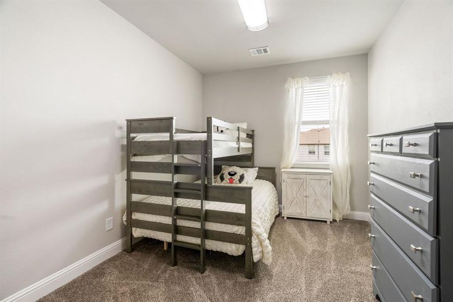 Carpeted bedroom featuring neutral wall tones, a single window with blinds, baseboard molding, and a ceiling-mounted light fixture Carpeted bedroom featuring neutral wall tones, a single window with blinds, baseboard molding, and a ceiling-mounted light fixture