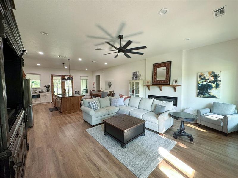 Living room with recessed lighting, a fireplace, light wood-style flooring, and a ceiling fan Living room with recessed lighting, a fireplace, light wood-style flooring, and a ceiling fan