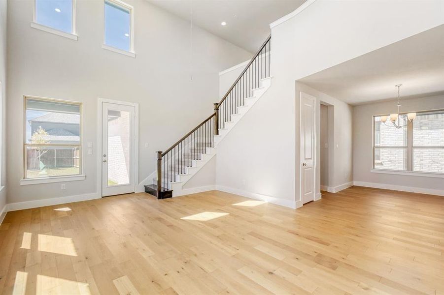 Entrance foyer with light wood-style floors, a chandelier, and a high ceiling