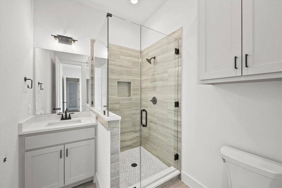 Bathroom featuring hardwood / wood-style flooring, toilet, an enclosed shower, and vanity