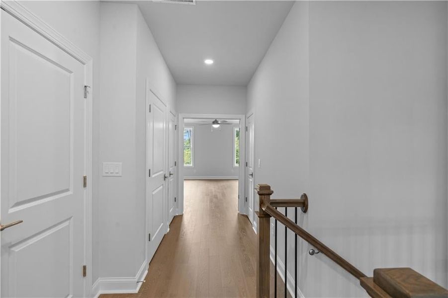 Corridor with wood finished floors, an upstairs landing, and recessed lighting Corridor with wood finished floors, an upstairs landing, and recessed lighting