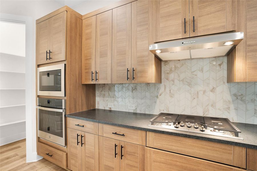 A contemporary kitchen features sleek wood cabinetry, stone countertops, and modern stainless steel appliances. A contemporary kitchen features sleek wood cabinetry, stone countertops, and modern stainless steel appliances.