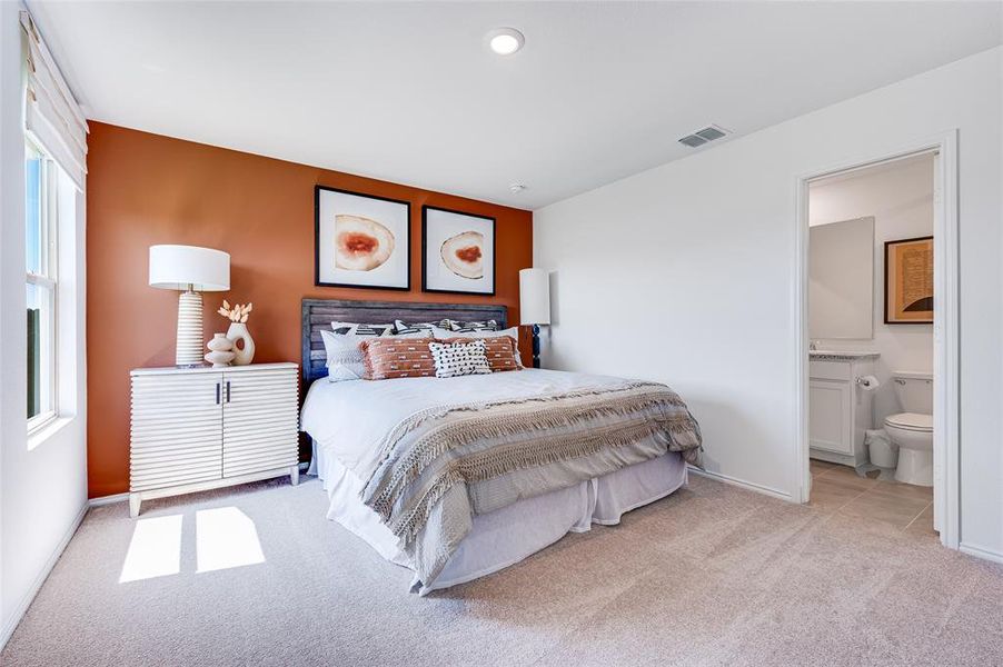 Carpeted bedroom with ensuite bathroom and multiple windows