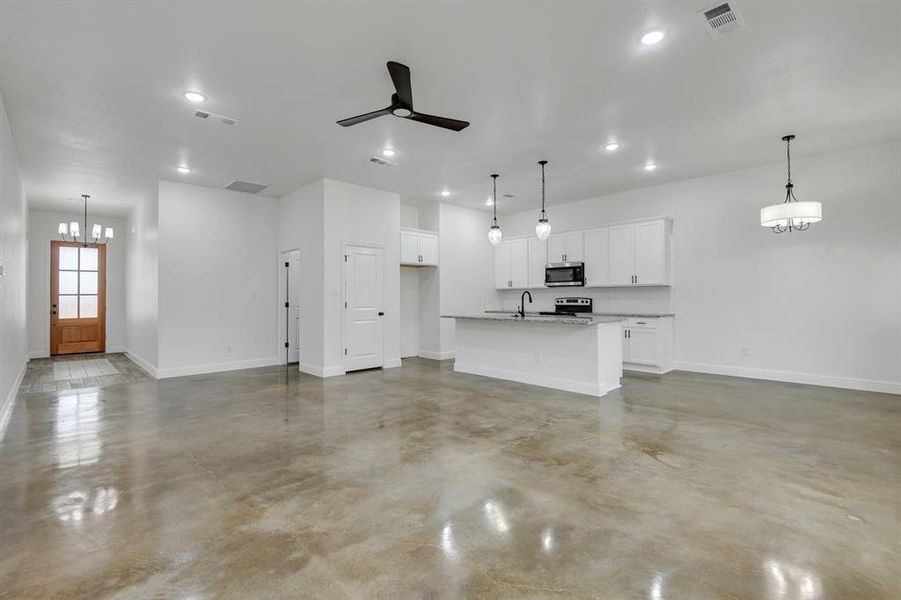 Unfurnished living room with a chandelier, a ceiling fan, finished concrete floors, and recessed lighting