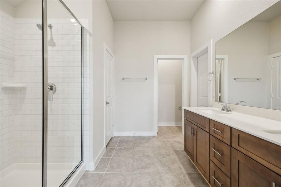 Ensuite primary bathroom featuring a walk-in shower and dual sinks